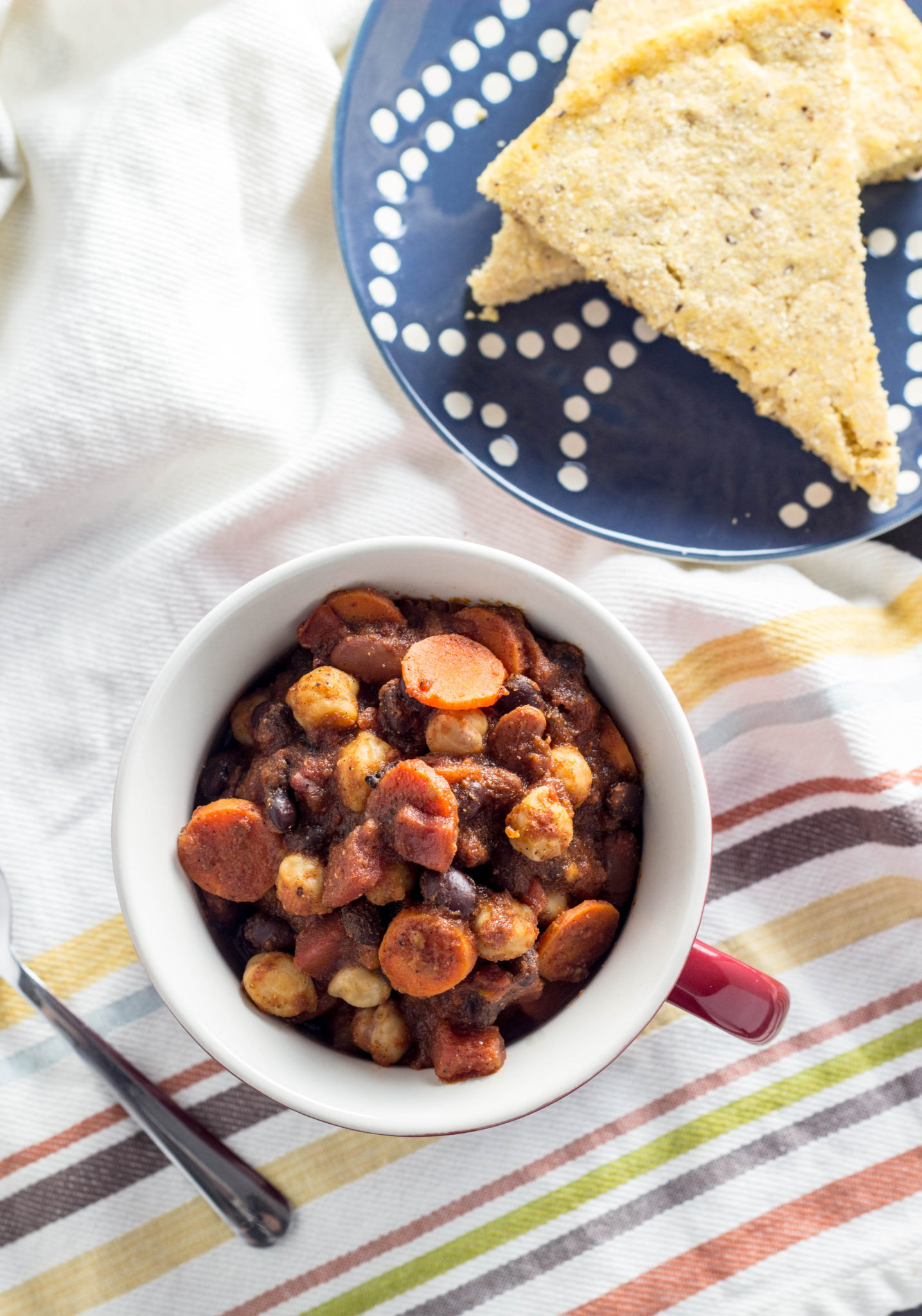 Top view of Vegan Three Bean Chili in a mug with cornbread to the side. 