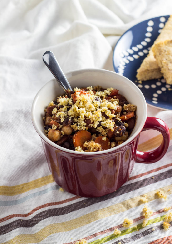 Chili with cornbread crumbles over the top in a red mug. 