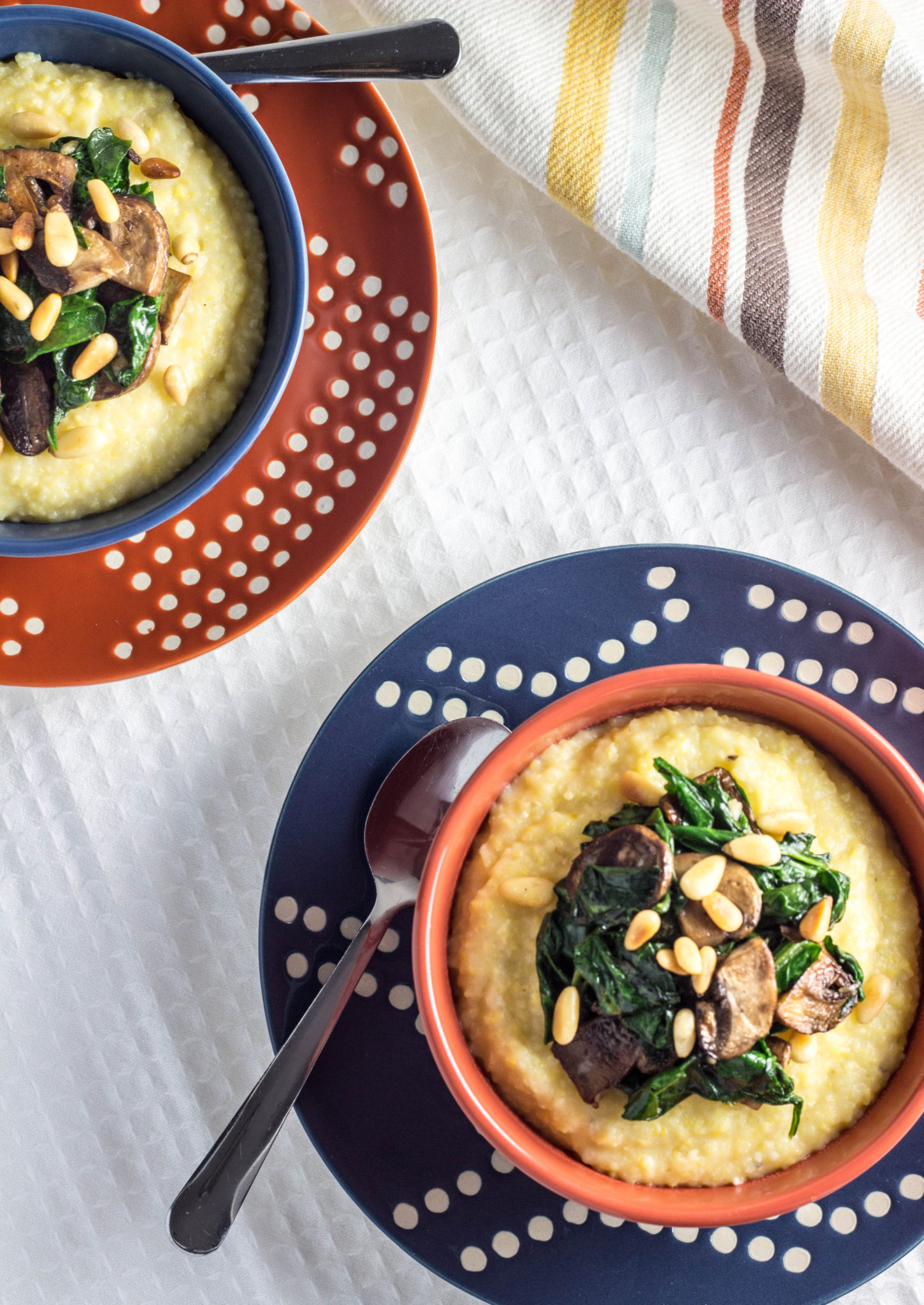 Creamy Polenta with Mushrooms, Spinach, and Toasted Pine Nuts-A simple, no fuss creamy polenta topped with sautéed baby portabella mushrooms, lightly wilted garlicky spinach, and freshly toasted pine nuts. This warm and comforting dish comes together in about 30 minutes and makes a delicious, quick meal on chilly nights.
