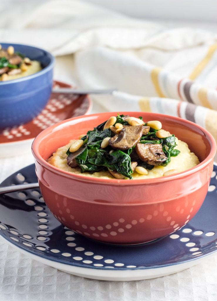 Creamy Polenta with Mushrooms, Spinach, and Toasted Pine Nuts-A simple, no fuss creamy polenta topped with sautéed baby portabella mushrooms, lightly wilted garlicky spinach, and freshly toasted pine nuts. This warm and comforting dish comes together in about 30 minutes and makes a delicious, quick meal on chilly nights.