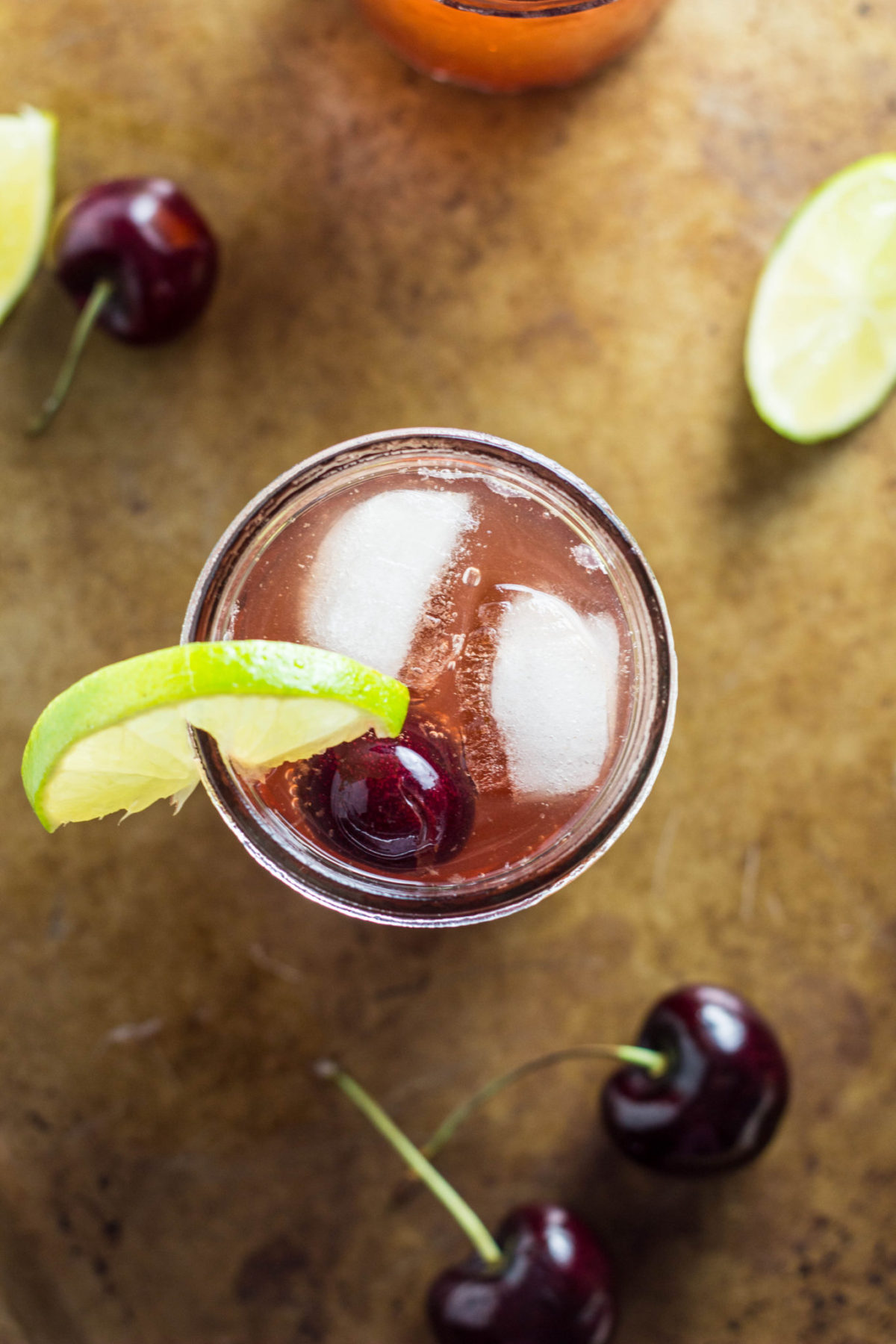 Top view of Kid Friendly Cherry Lime Spritzer with fruit around the glass. 