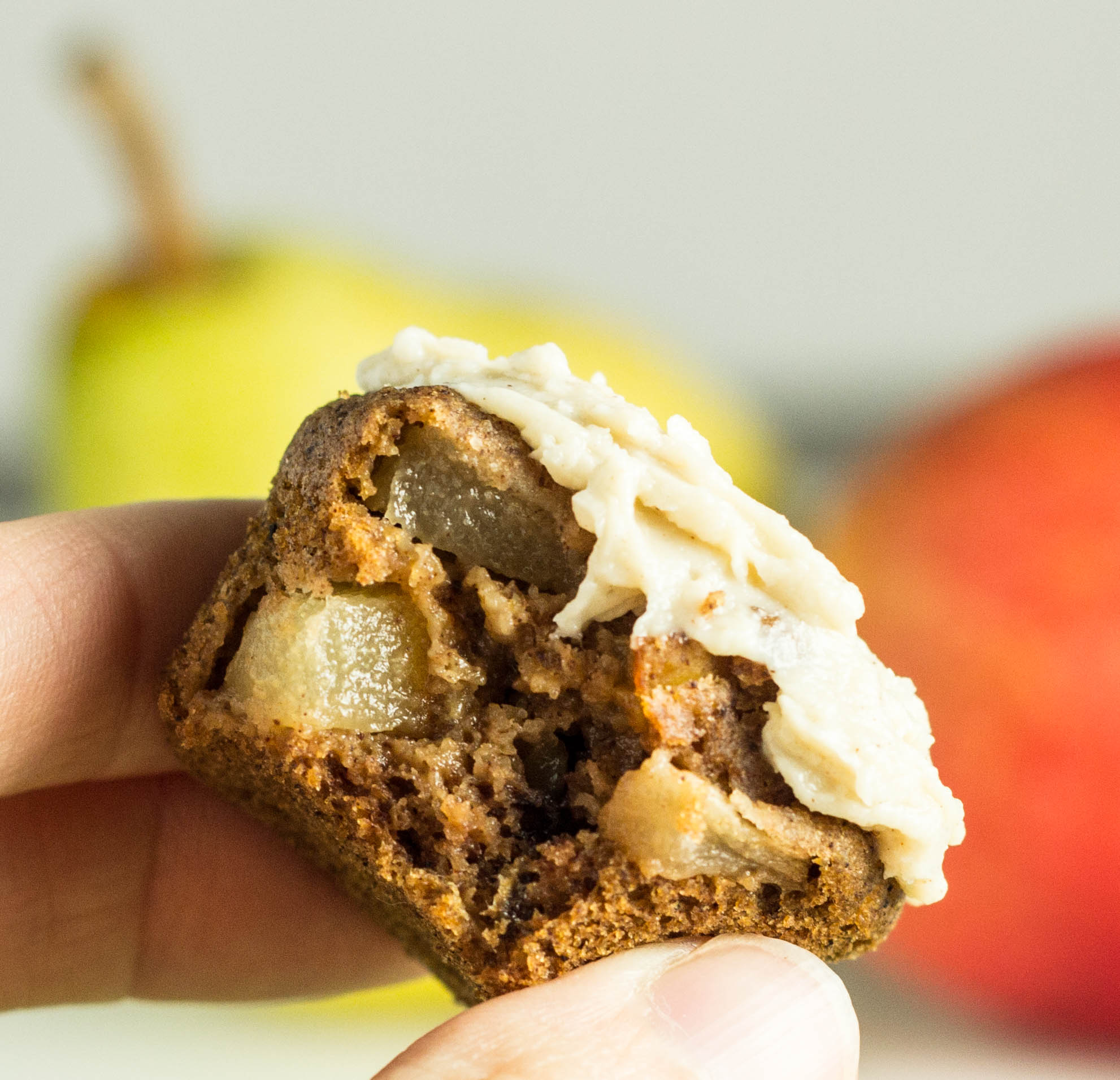Close up of frosted Cinnamon Pear Mini Muffins in hand. 