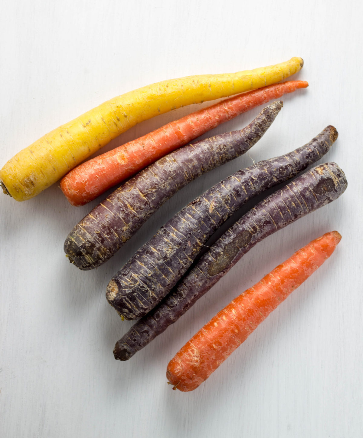 Top view of whole rainbow carrots on a white background.