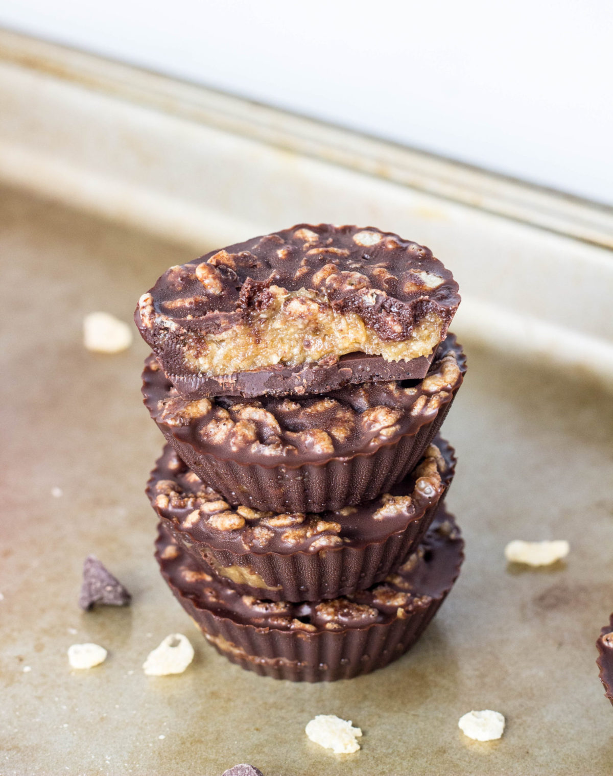 Stack of four candy cups with the top one cut in half to show the date caramel filling. 