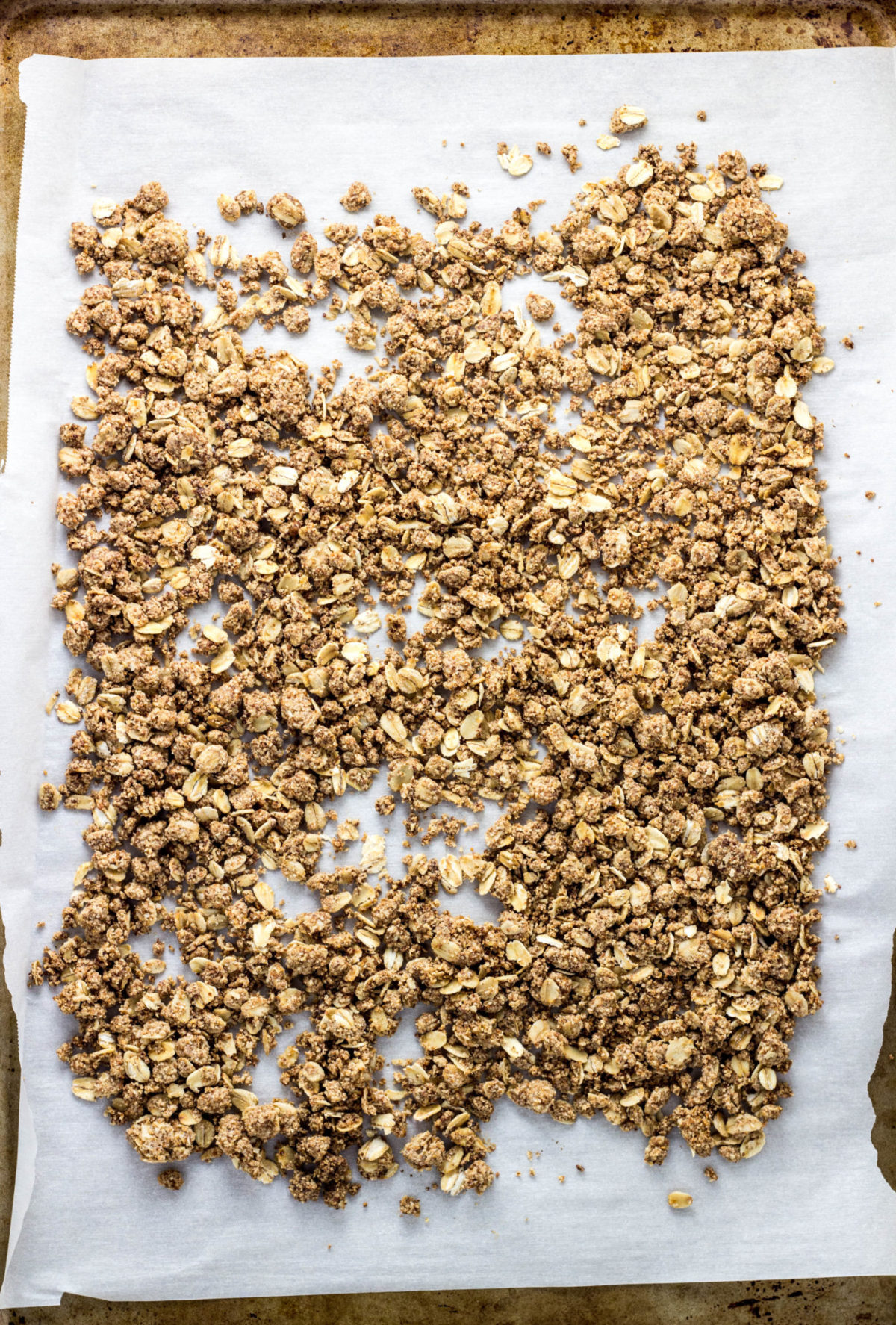 Top view of granola on a parchment paper lined baking sheet. 