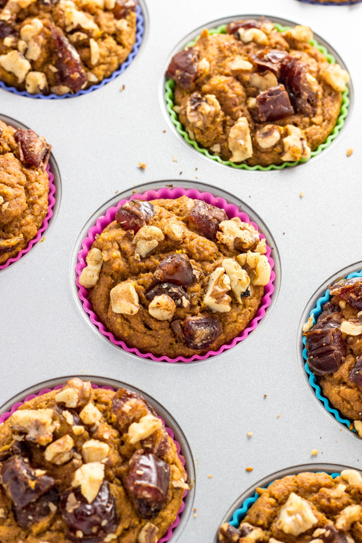 Vegan Date & Nut Crumble Pumpkin Muffins in a muffin pan. 