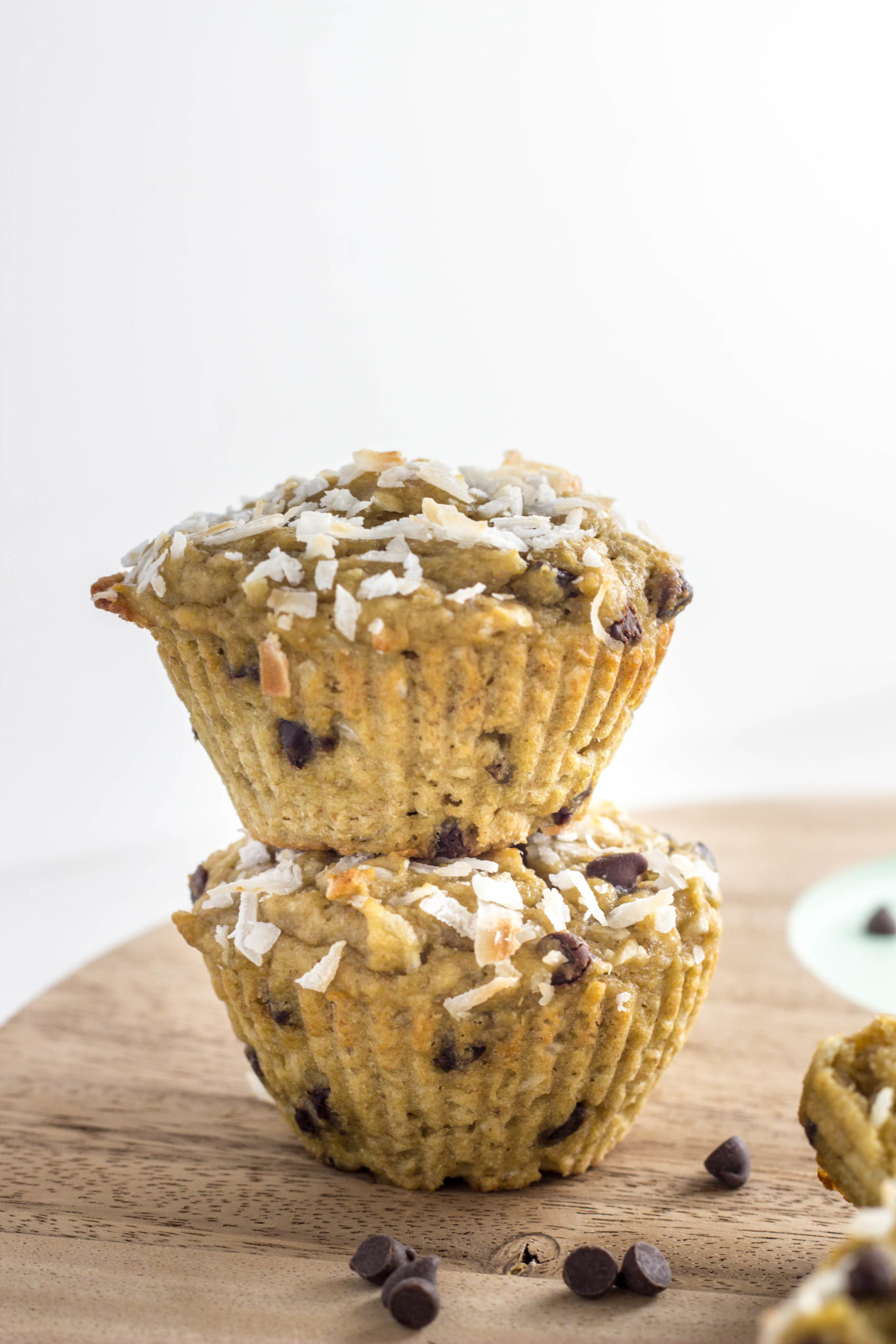 Close up side view of two muffins stacked on a wooden cutting board.