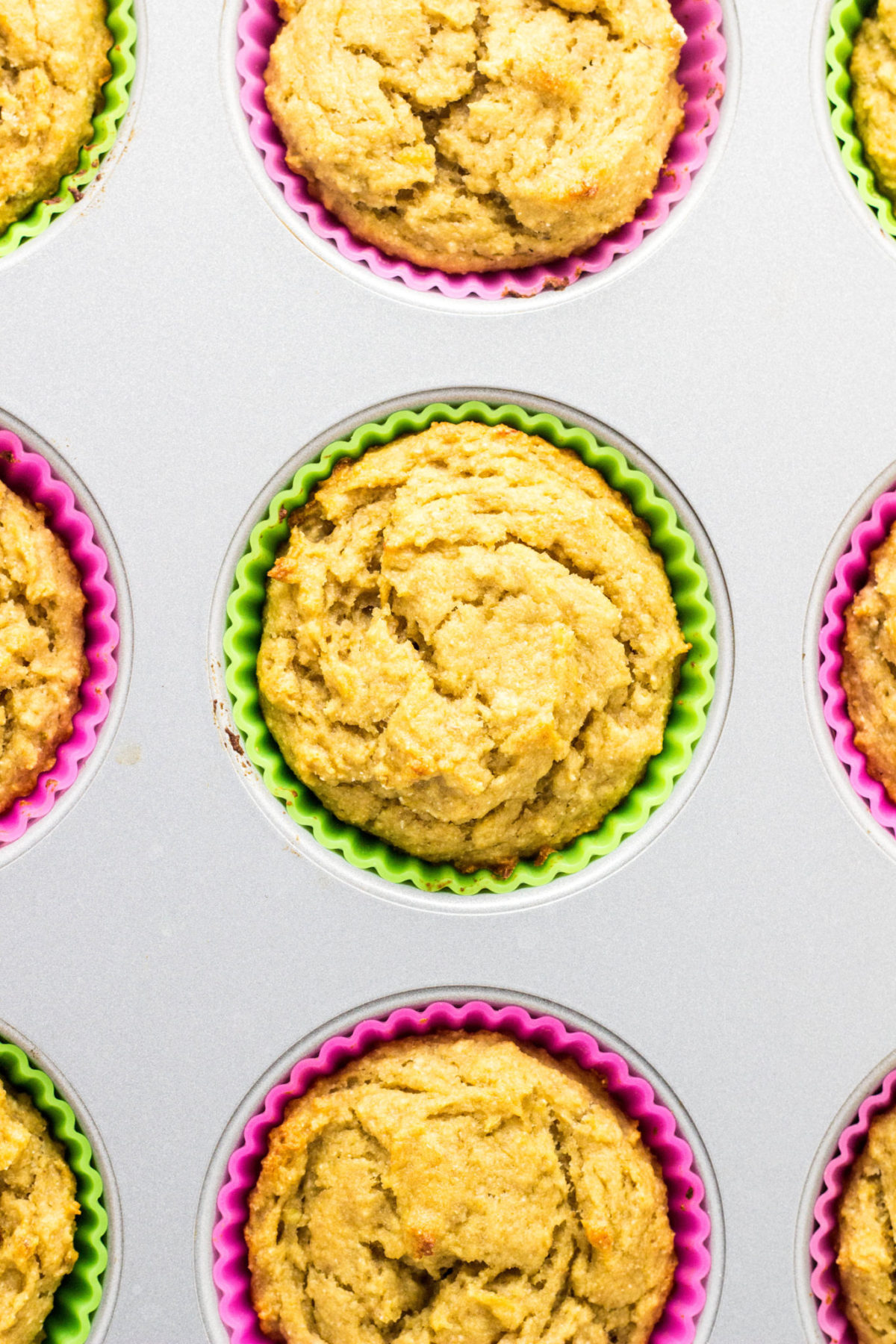 Top view of Vegan Lime Avocado Muffins with multi colored silicone baking cups in a muffin pan. 