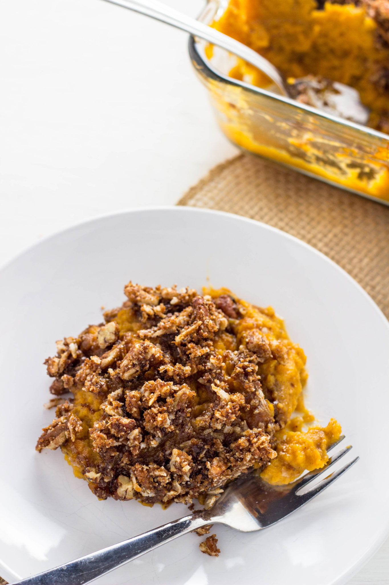 Side view of Vegan Sweet Potato Casserole in a white plate with a fork. 