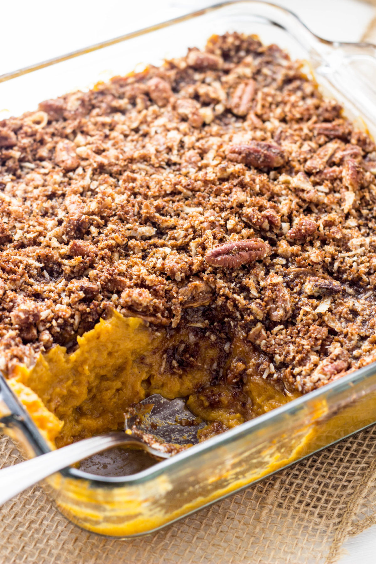 Vegan Sweet Potato Casserole in a glass baking dish with a portion removed. 