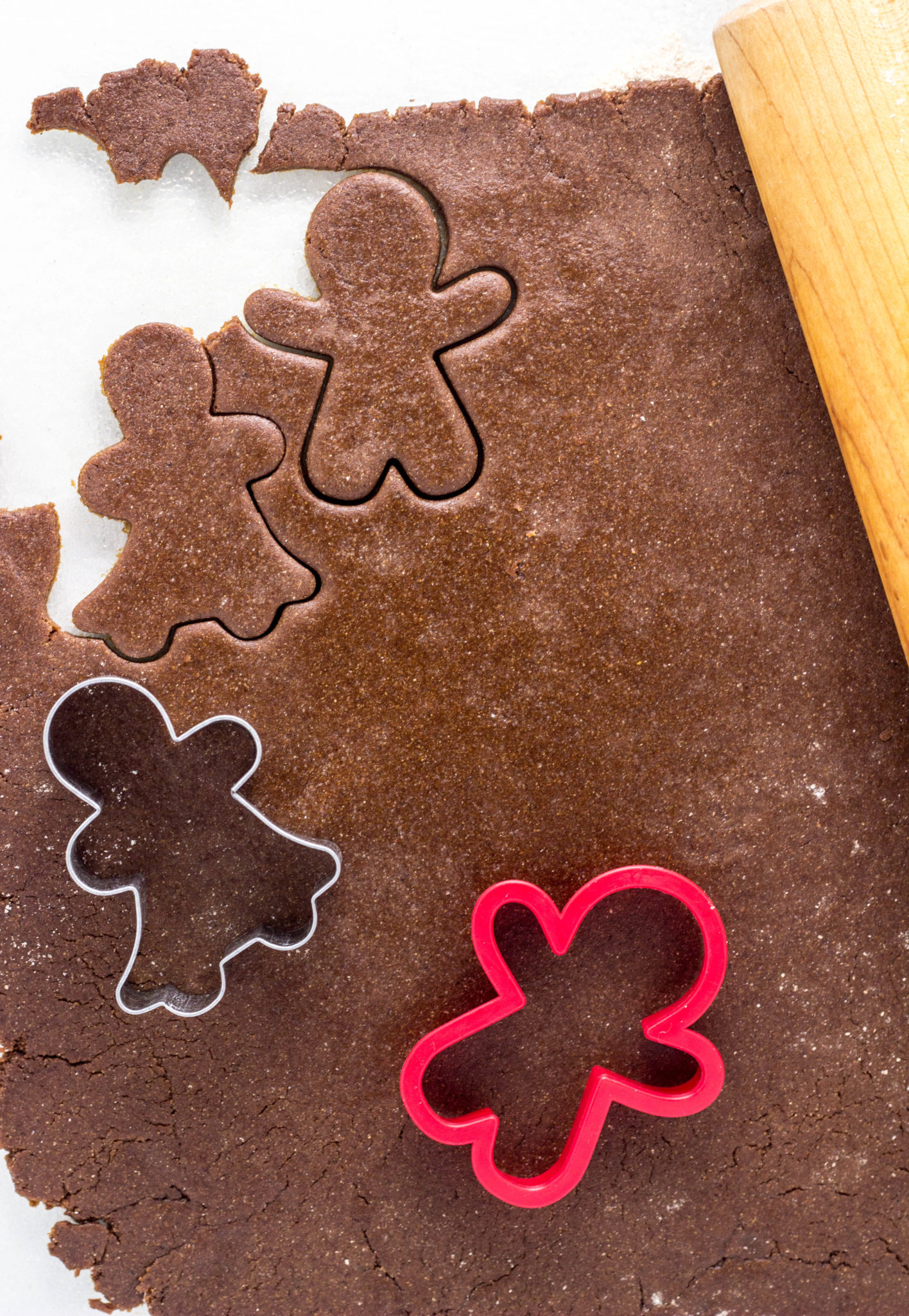 Top view of gingerbread dough rolled out and cookie cutters. 