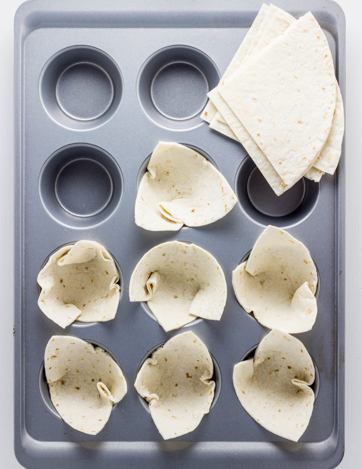 Top view of mudding pan with tortillas  folded into cups. 
