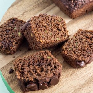 Four slices of Chocolate Zucchini Bread Mini Loaf on a round wooden board.