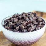 Close up side view of a bowl filled with Vegan Chocolate Covered Raisins.