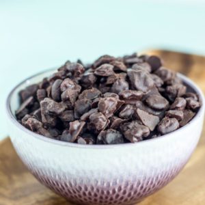 Close up side view of a bowl filled with Vegan Chocolate Covered Raisins.