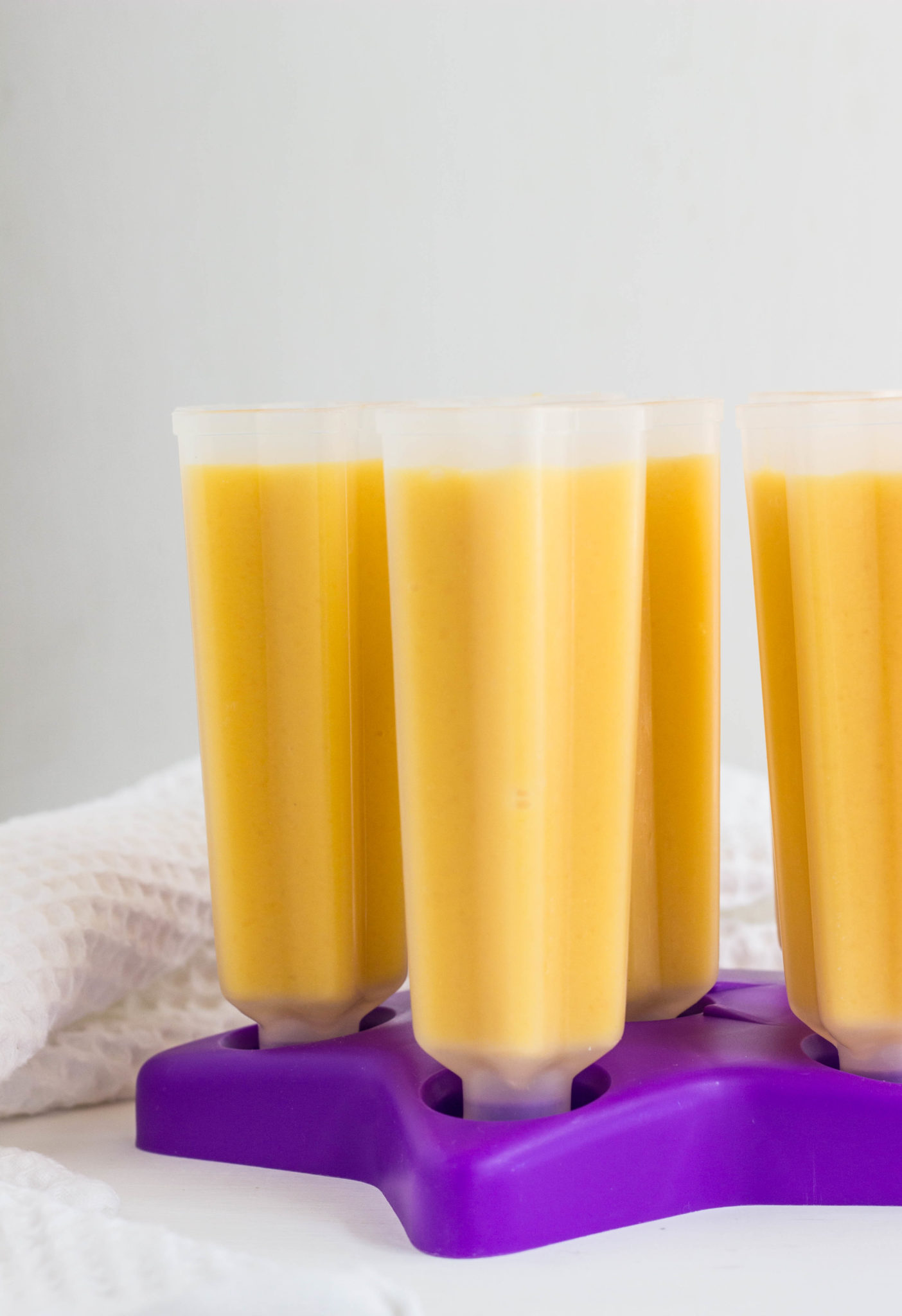Side view of popsicle molds filled with cantaloupe molds before freezing. 