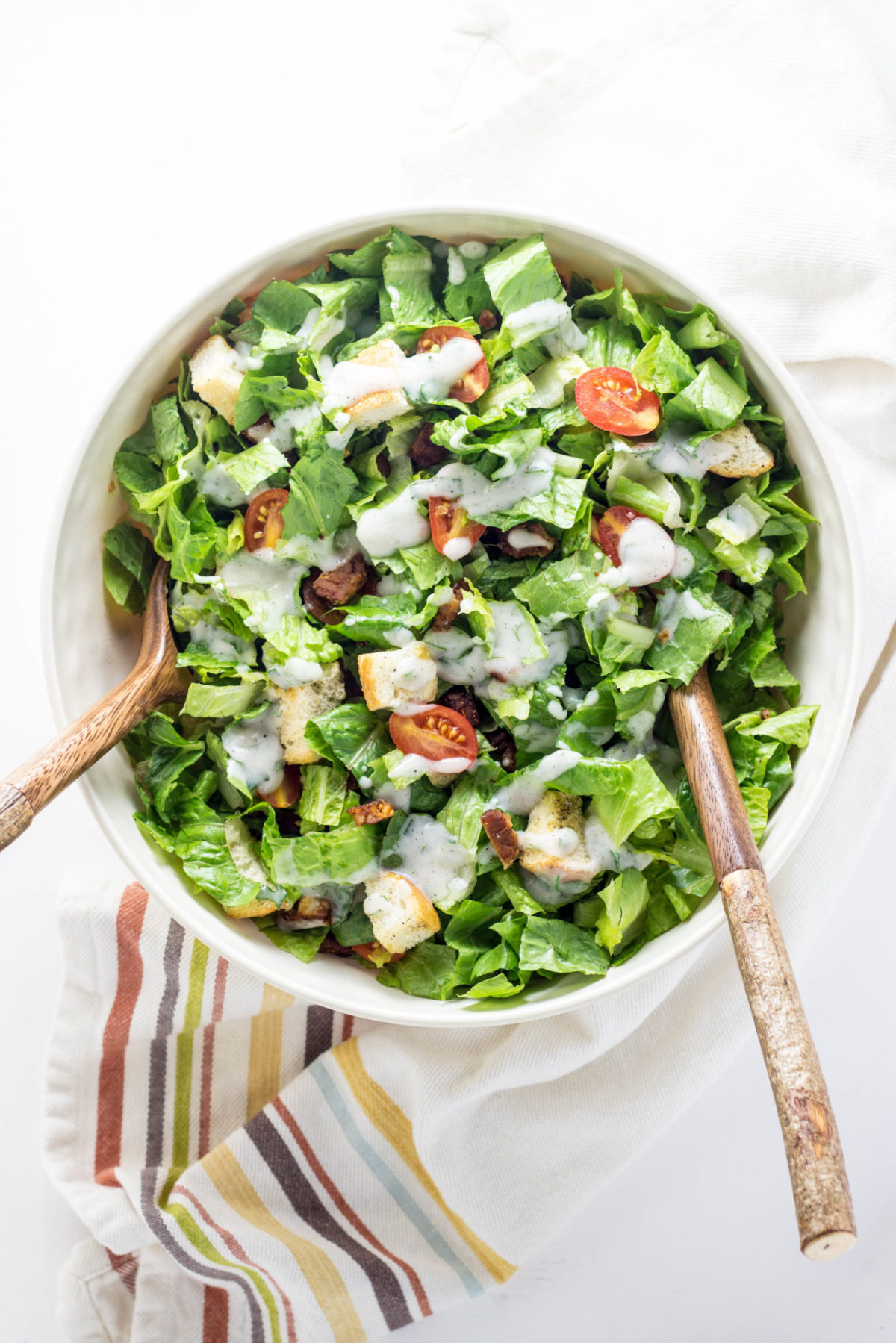 Top view of Vegan BLT Salad in bowl with wooden salad servers.