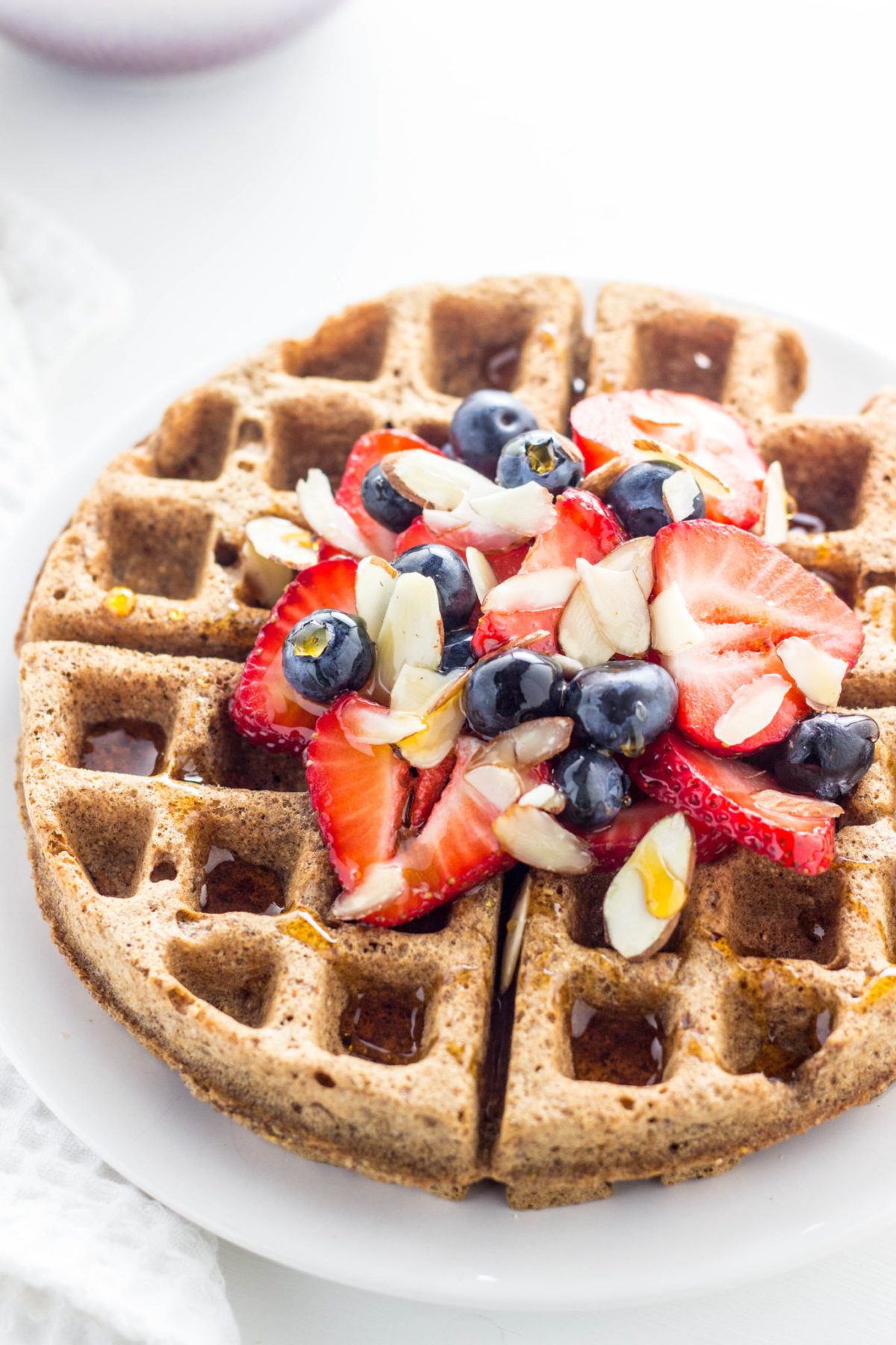 Vegan Cinnamon Rye Waffles topped with fresh fruit and syrup. 