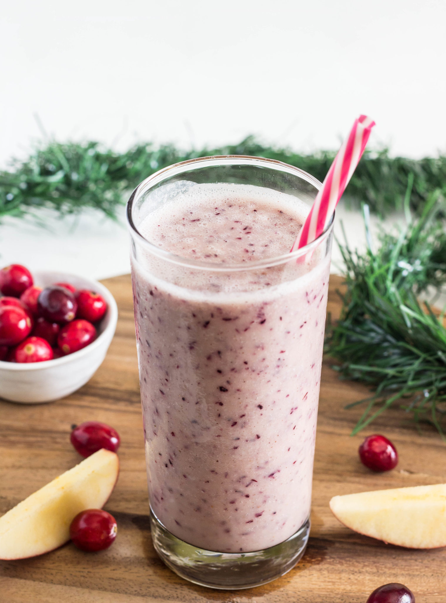 Side view of Cranberry Apple Smoothie in a tall glass with a straw. 