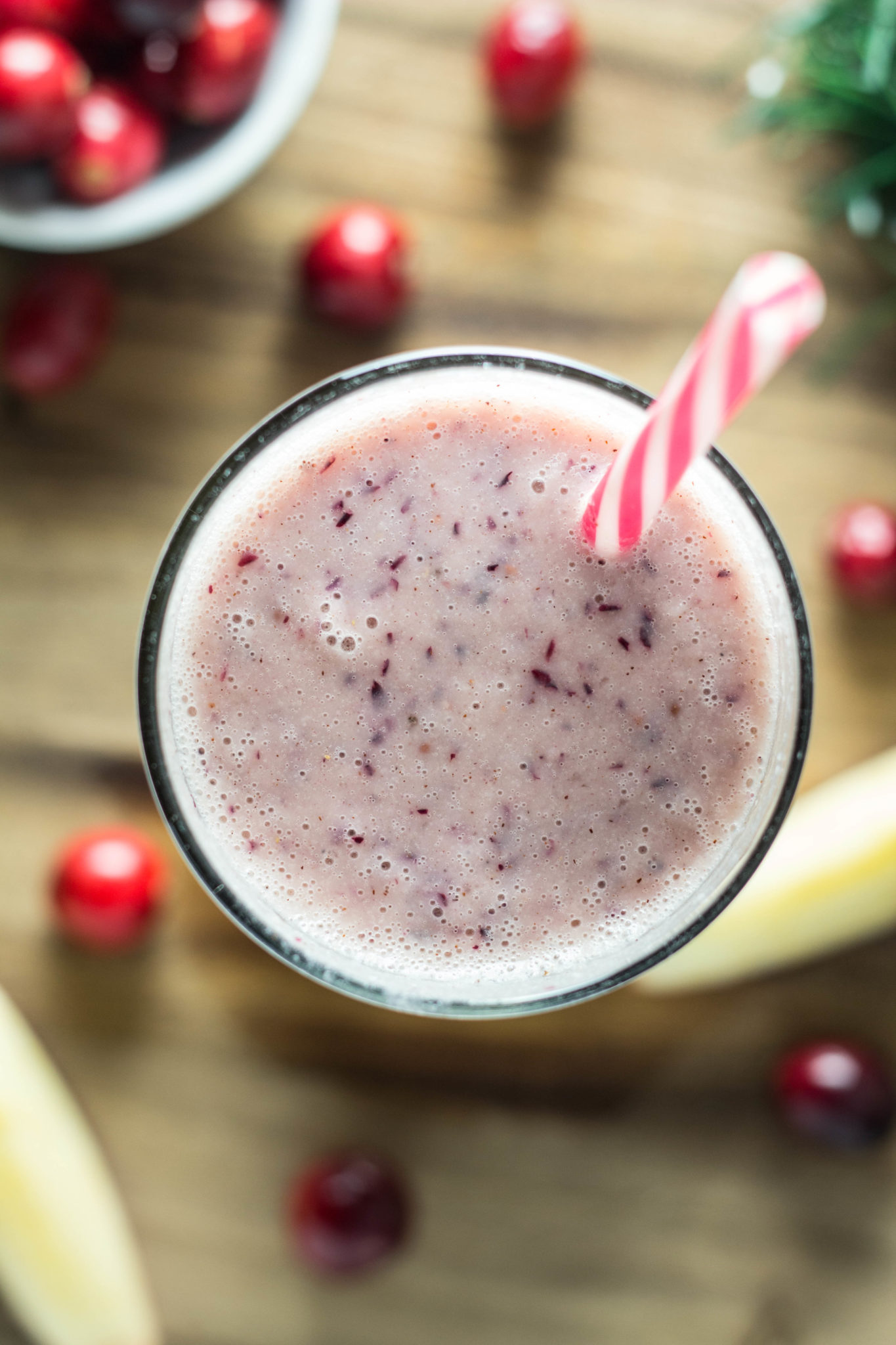 Overhead close up of shot of Cranberry Apple Smoothie in a glass with a straw. 