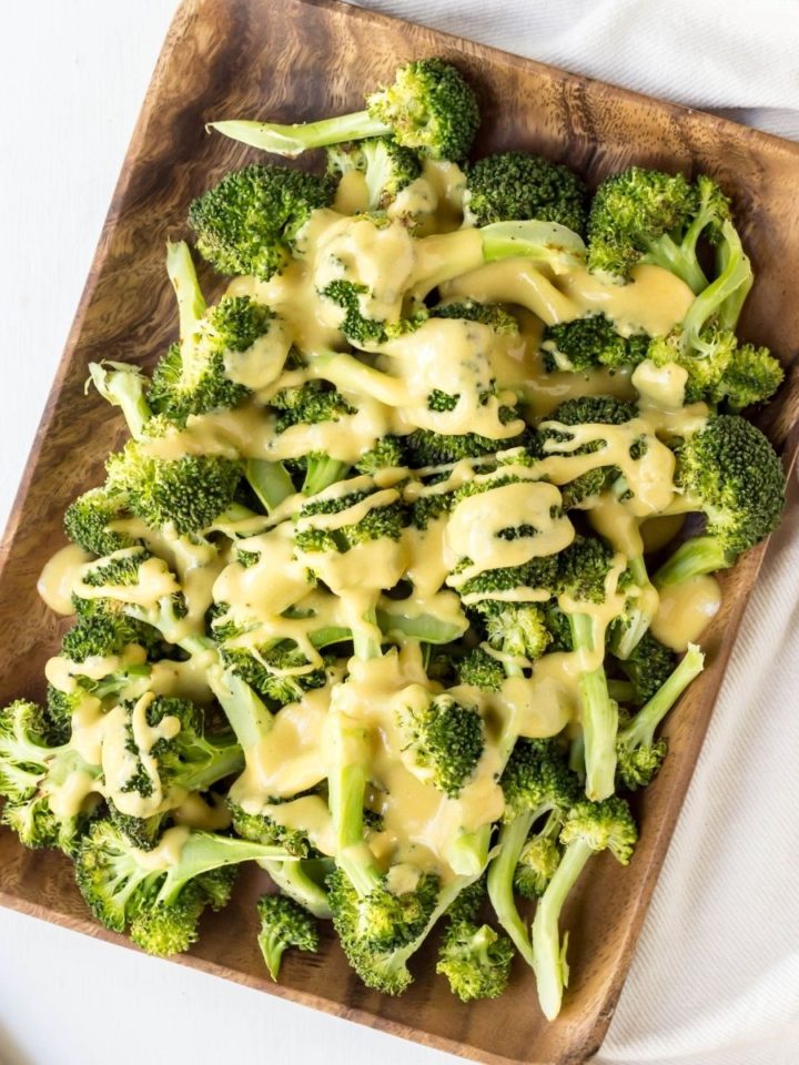 Top view of Roasted Broccoli with Vegan Cheese Sauce on a rectangular wooden serving plate.