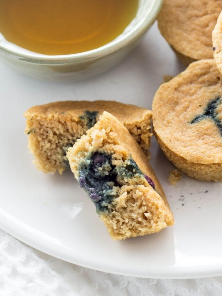 Close up view of Vegan Pancake Mini Muffin Bites on a white plate with a dipping bowl of maple syrup on the side.