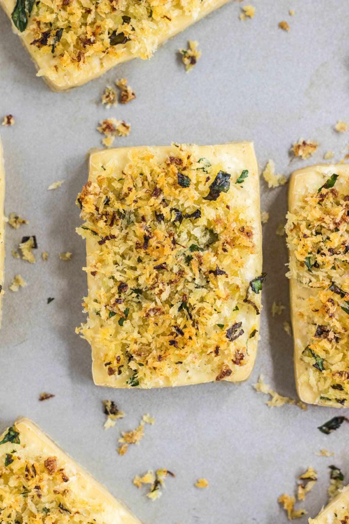 Close up of tofu with bread crumbs on top on a baking sheet.