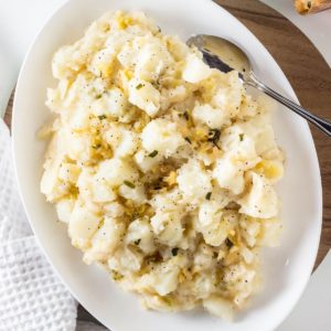 Top view of Vegan Kimchi Potato Salad on a white serving plate with a spoon.