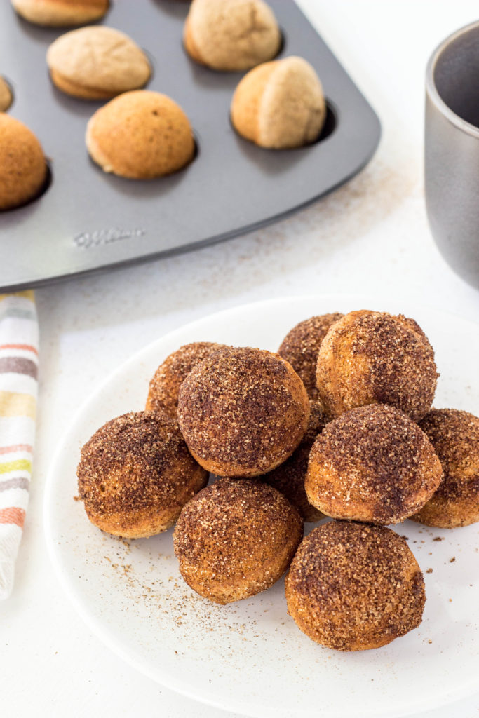 Stack of Baked Cinnamon Sugar Doughnut Holes on white plate. 