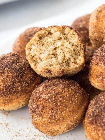 Side view close up of a group of Baked Cinnamon Sugar Doughnut Holes. One of the doughnut holes shows the interior texture.