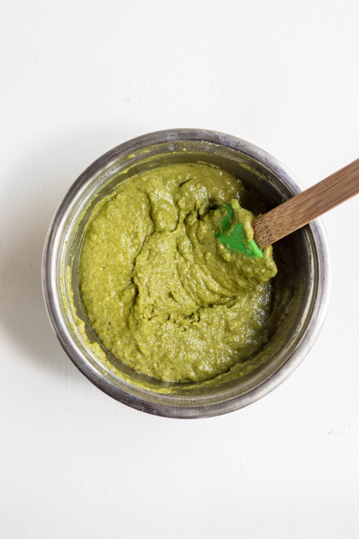 Green batter in a metal bowl with spatula