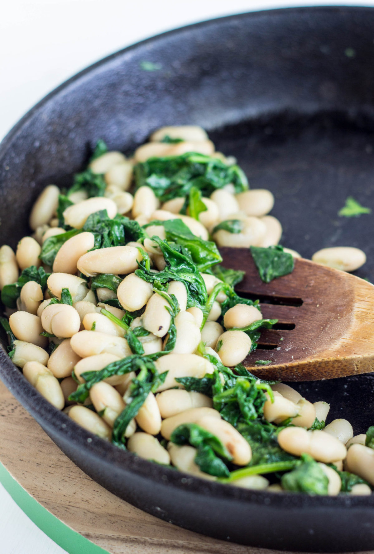 Image of white beans and sautéed spinach in a skillet.