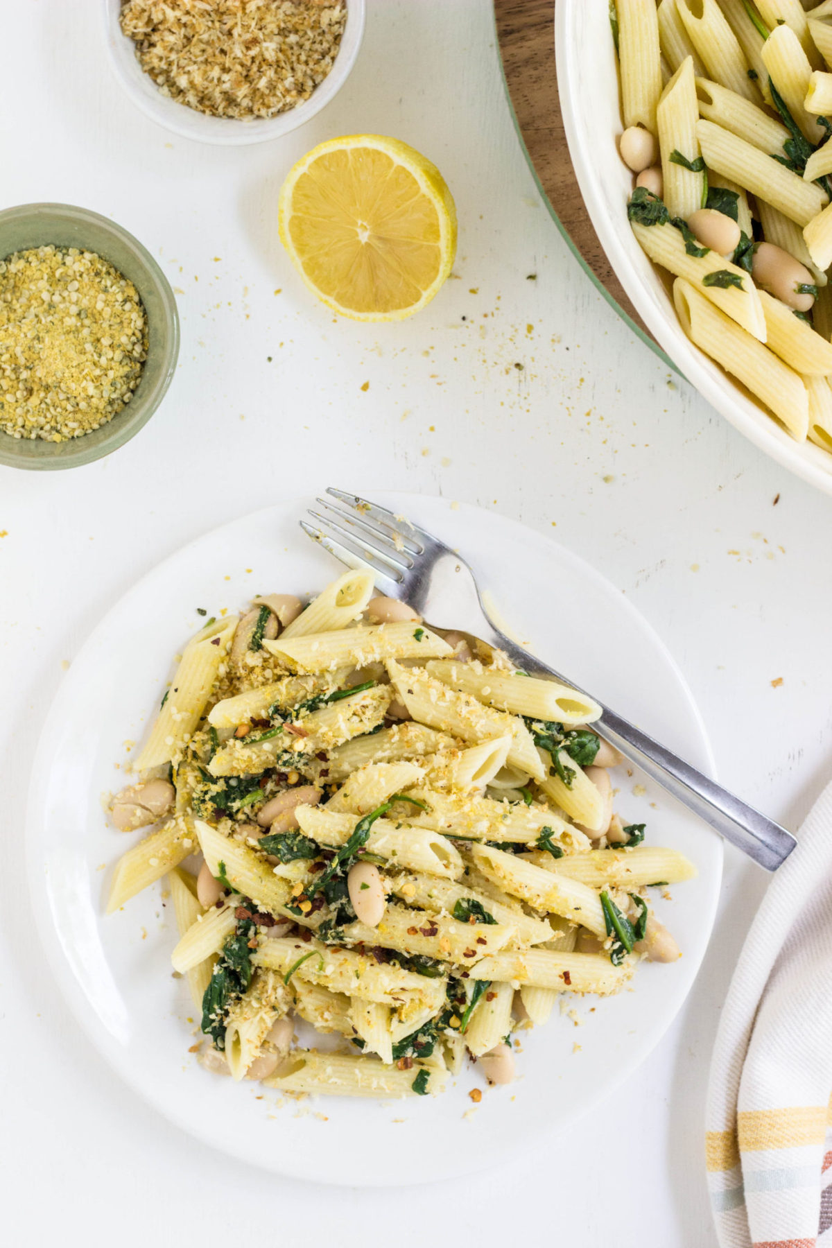 Top view of a plate of pasta with spinach and beans. 