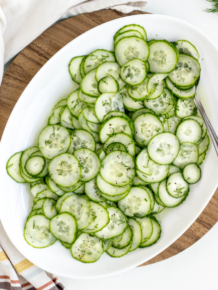 Top view of Simple Vegan Cucumber Salad on a white serving plater with spoon.
