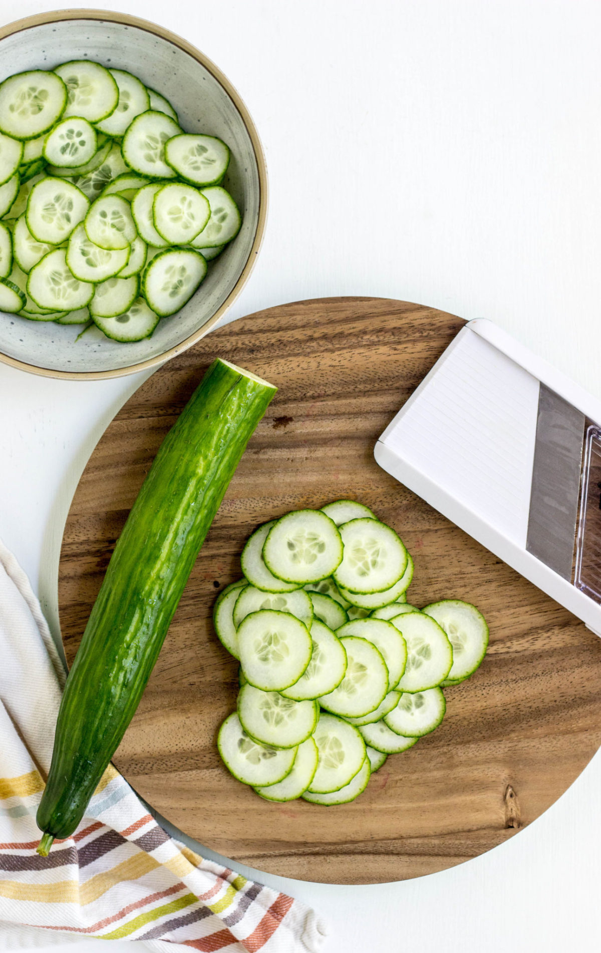 Cucumbers being sliced using a mandolin. 