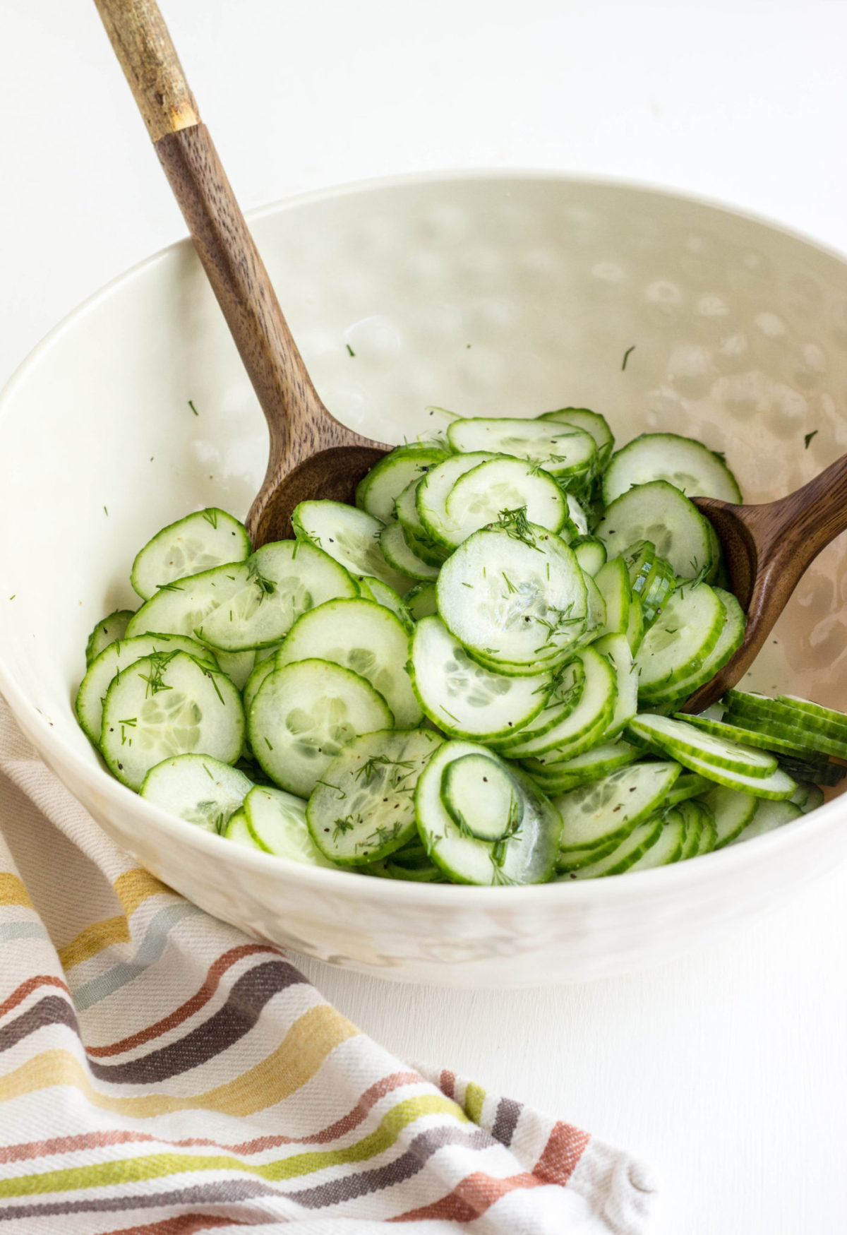 Bowl of Simple Vegan Cucumber Salad with wooden serving spoons. 
