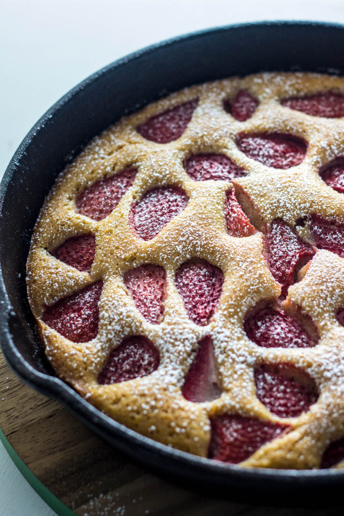 Side view close up of Vegan Berry Skillet Cake dusted with powdered sugar. 