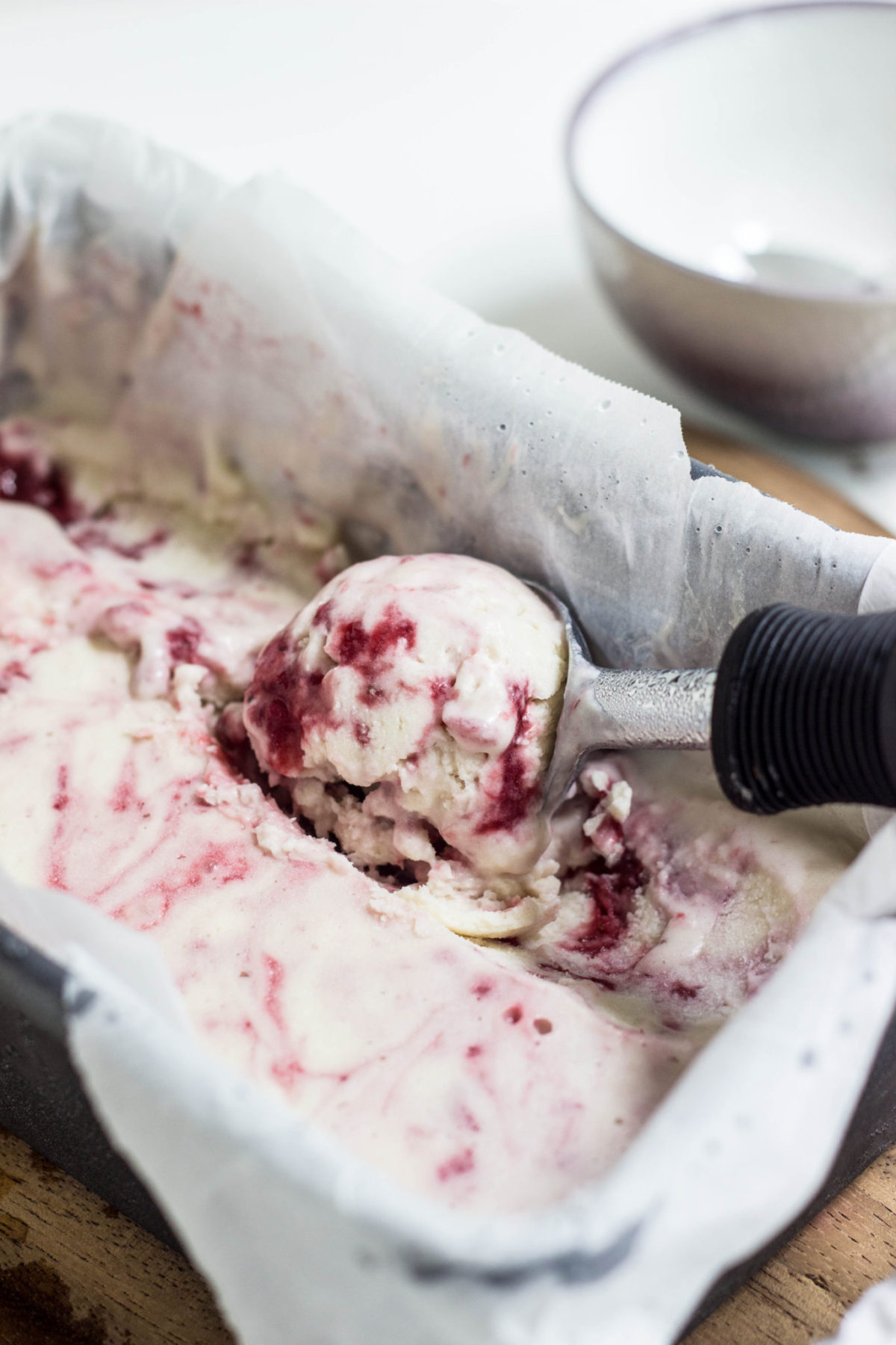 Side view of Strawberry Swirl Coconut Ice Cream being scooped from container.