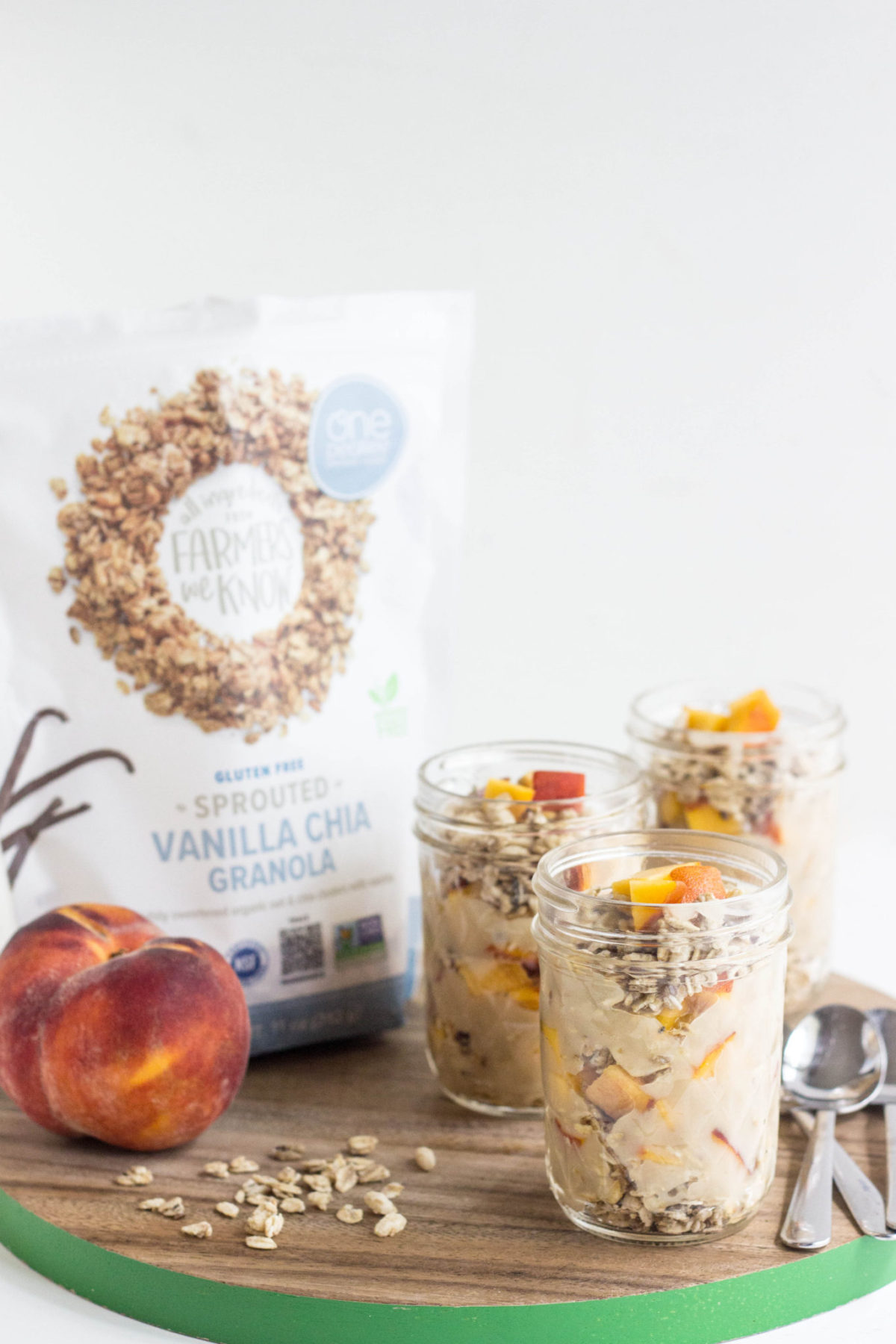 Side view of Healthy Peach Vanilla Parfait with a bag of granola and peach. 