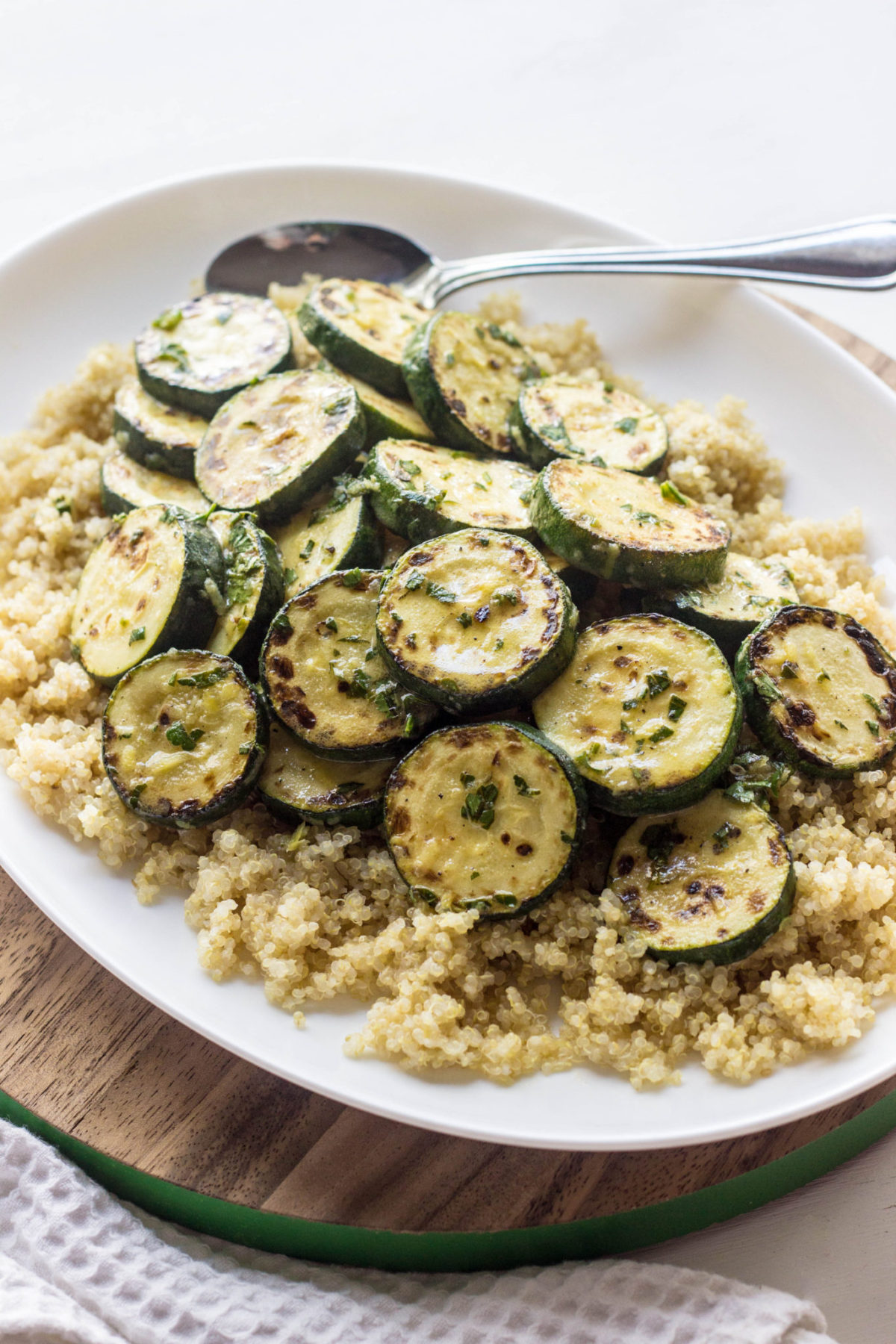 Charred Lemony Zucchini on a bed of quinoa served on a white serving plate.