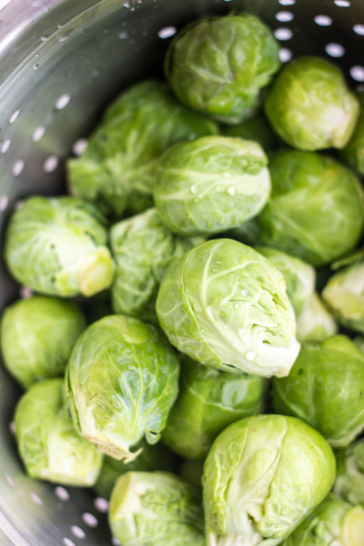 Whole Brussels sprouts in a metal colander.