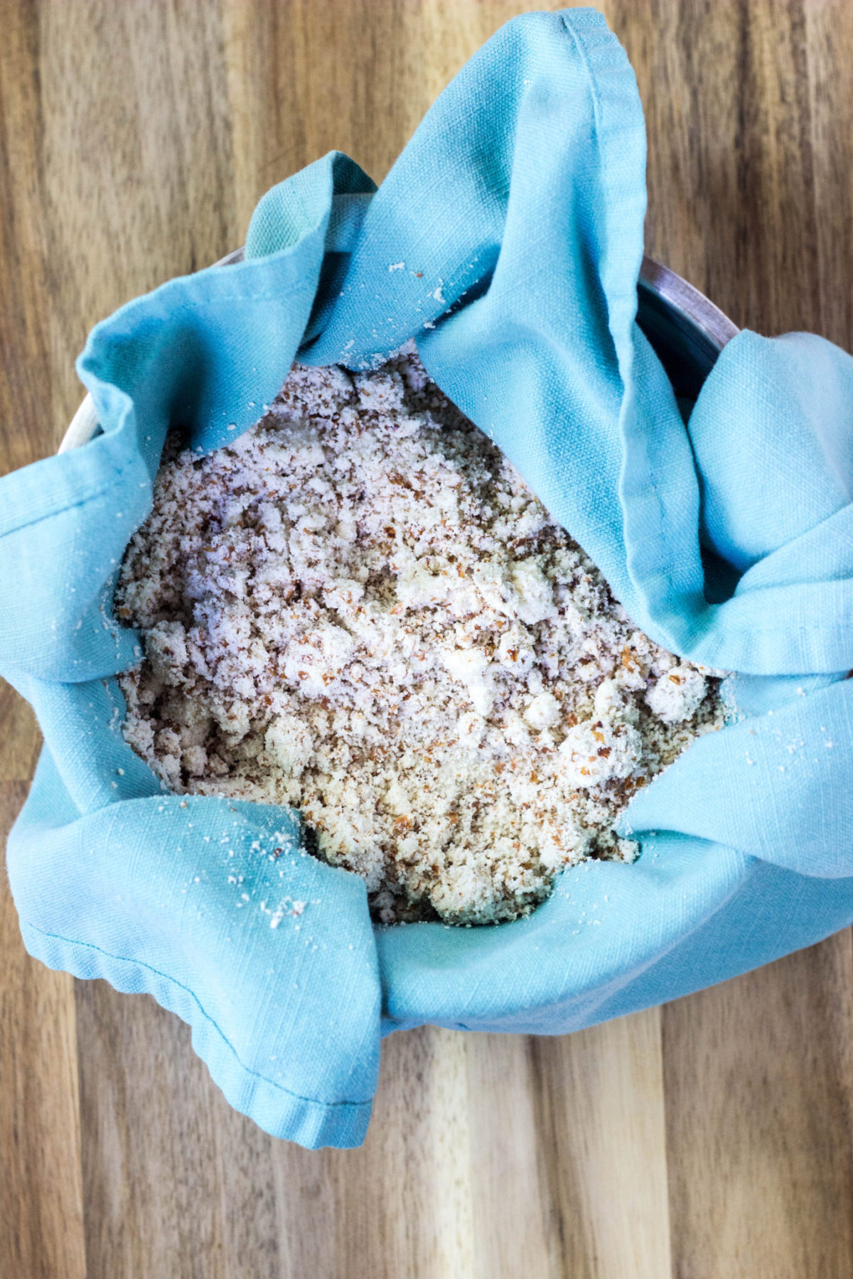 Top view of almond pulp in a blue towel in a bowl. 