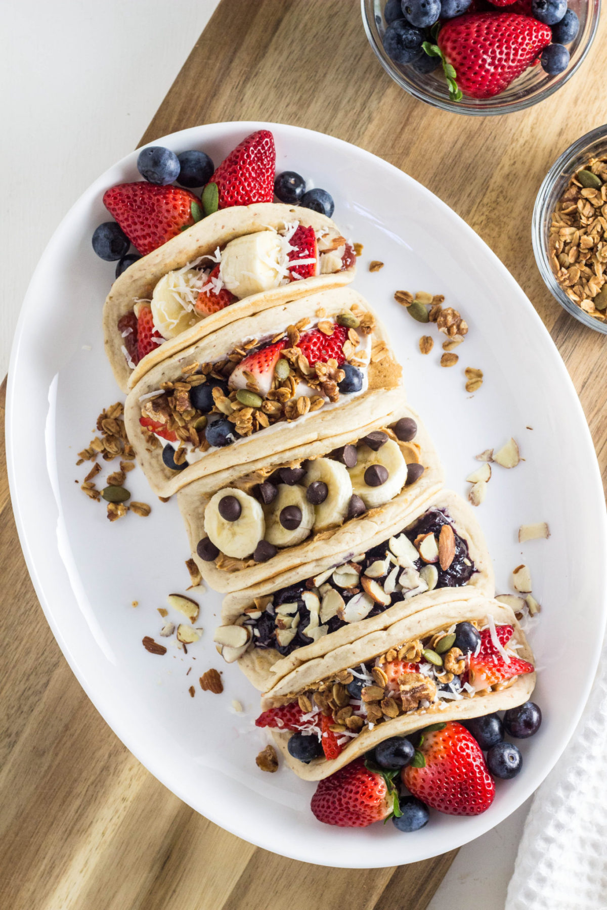 Top view of Vegan Almond Pancakes Tacos with different fillings and topping on a white plate. 