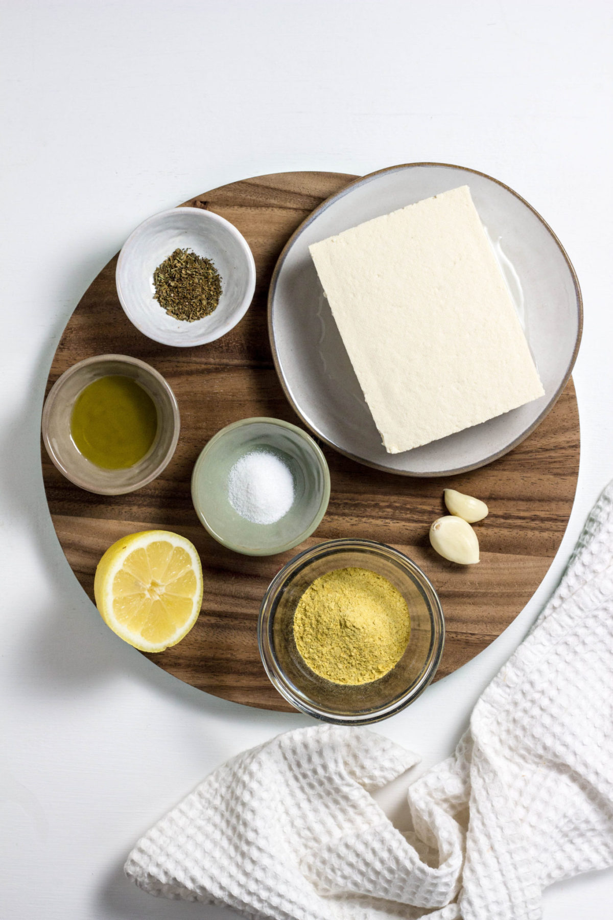 Ingredients for tofu ricotta on a round wooden board. 