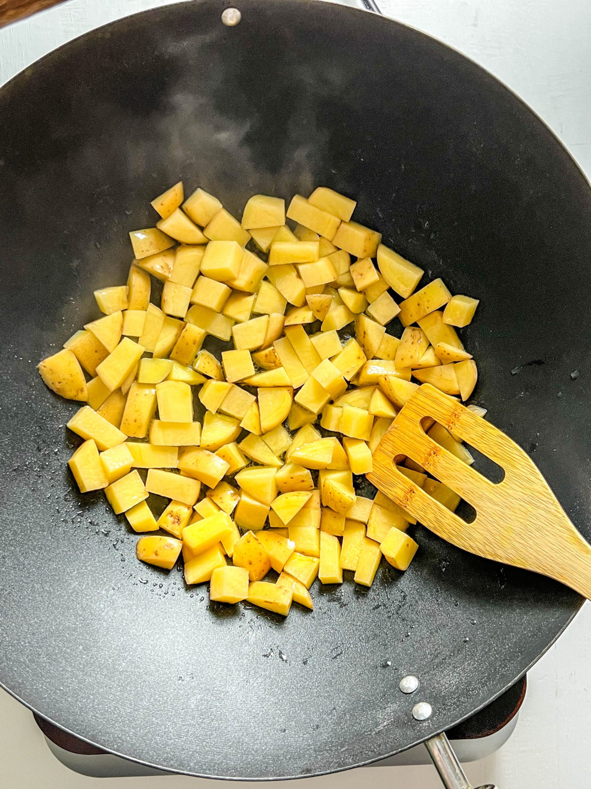 Overhead shot of potatoes frying in wok. 