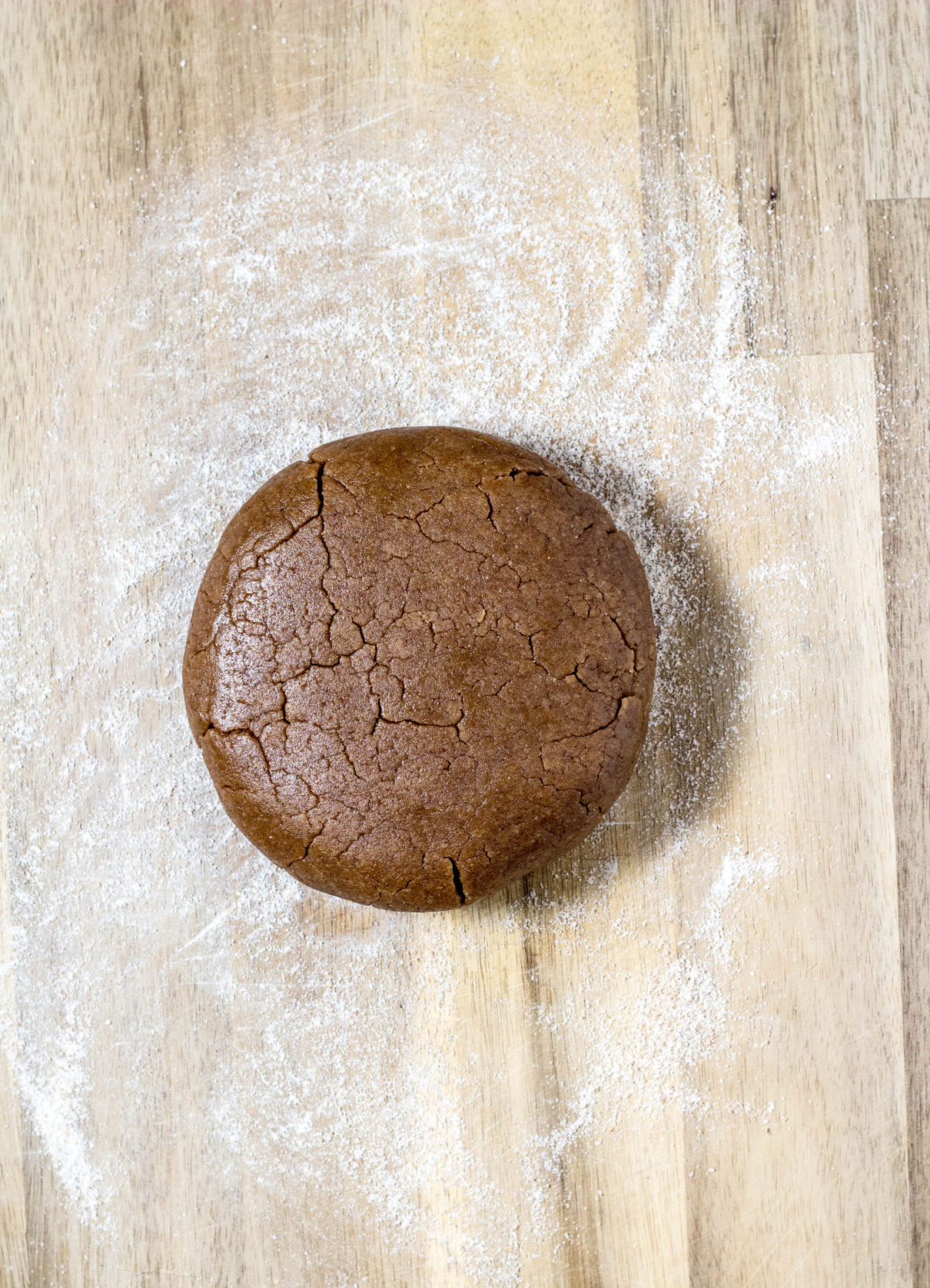 Overhead shot of dough in a disc on a floured wooden board. 
