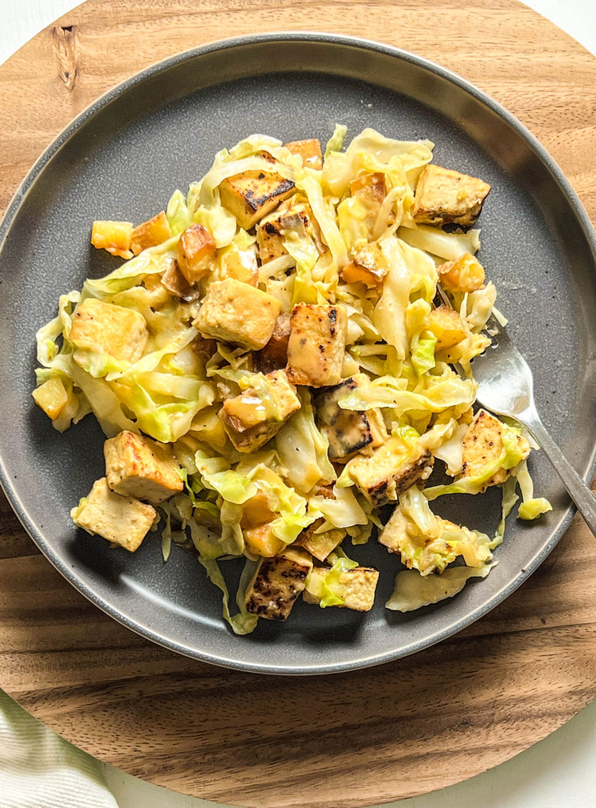 Close up overhead shot on Cabbage Stir Fry with Tofu on gray plate against wooden background. 