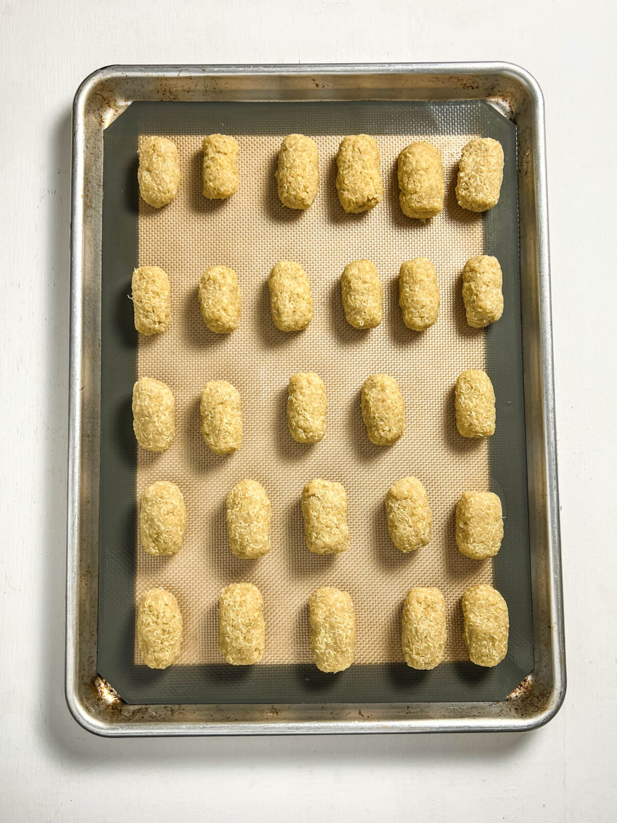 Overhead shot of quinoa tots on a baking sheet before being baked. 