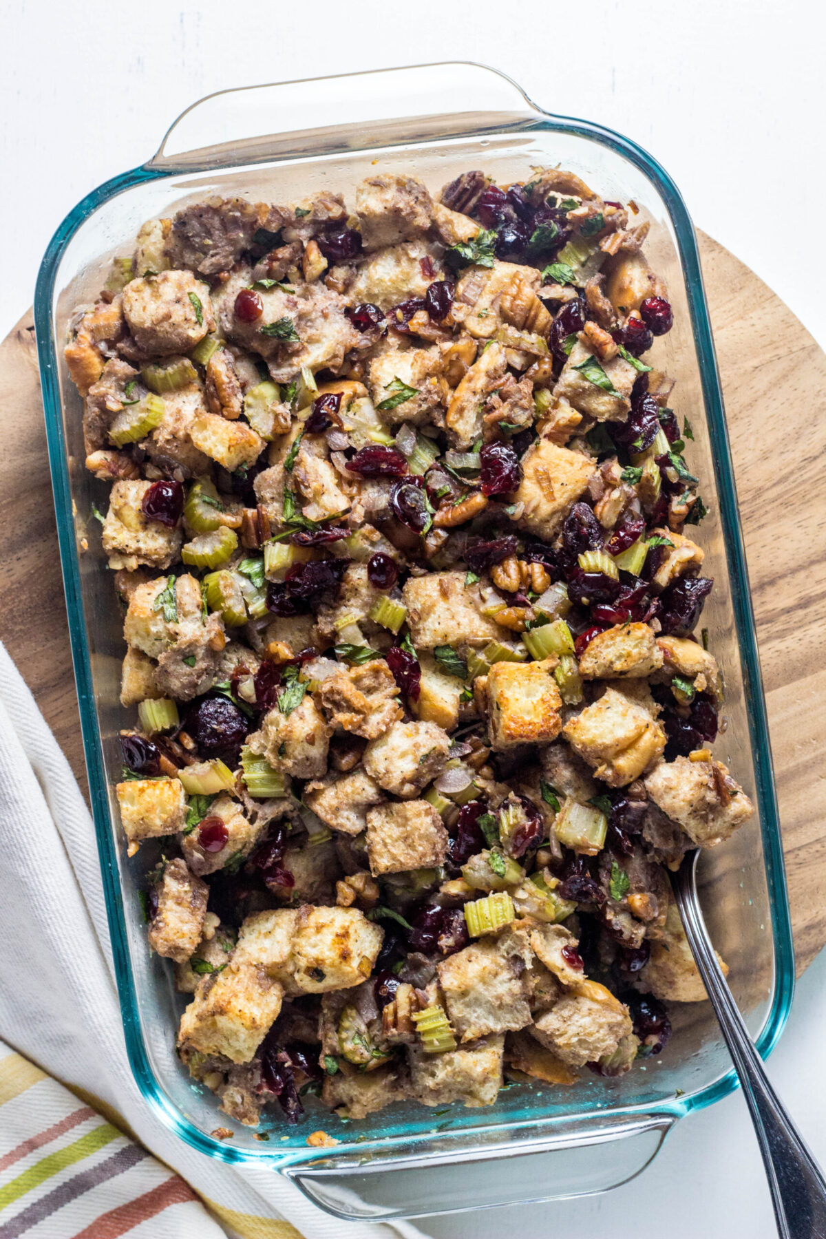 Over head shot of Vegan Cranberry Pecan Stuffing in a casserole dish on a wooden board. 