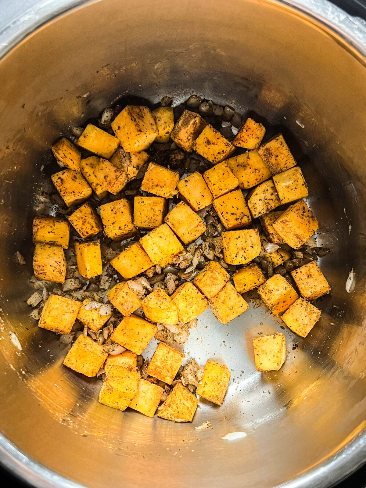 Overhead shot of butternut squash and onions sautéing in a pot. 